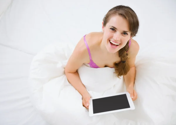 ベッドに座っていると、タブレット pc を使用して女性の笑みを浮かべてください。 — ストック写真