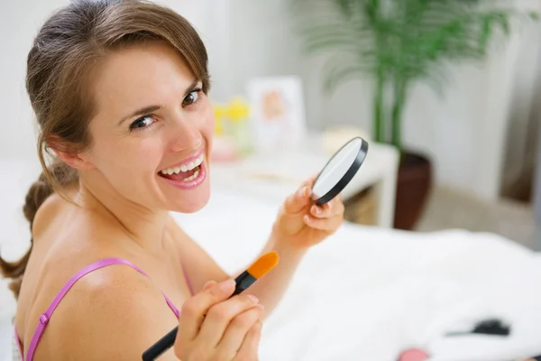Happy woman applying make up in bedroom — Stock Photo, Image