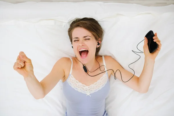 Portrait of girl laying on bed and listening music. Upper view — Stock Photo, Image