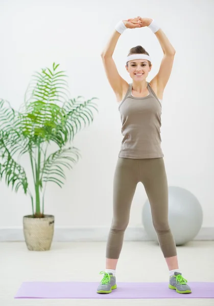 Mujer sana sonriente haciendo ejercicios de estiramiento —  Fotos de Stock