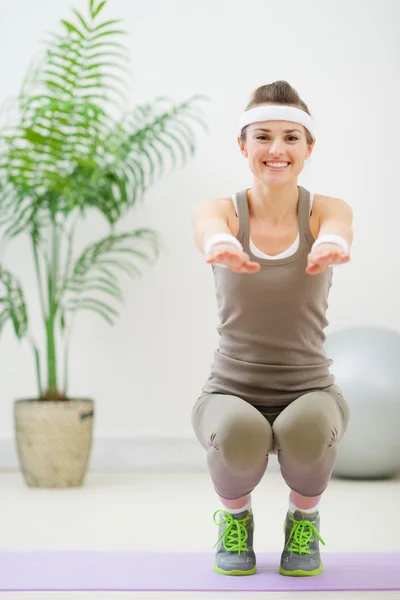 Smiling woman in sports wear squatting — Stock Photo, Image