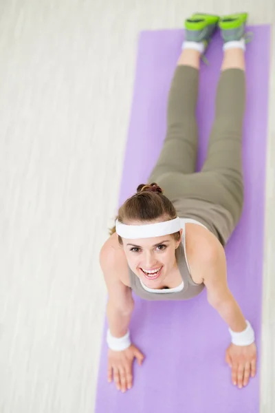 Donna fitness sorridente sul tappeto fitness facendo yoga — Foto Stock