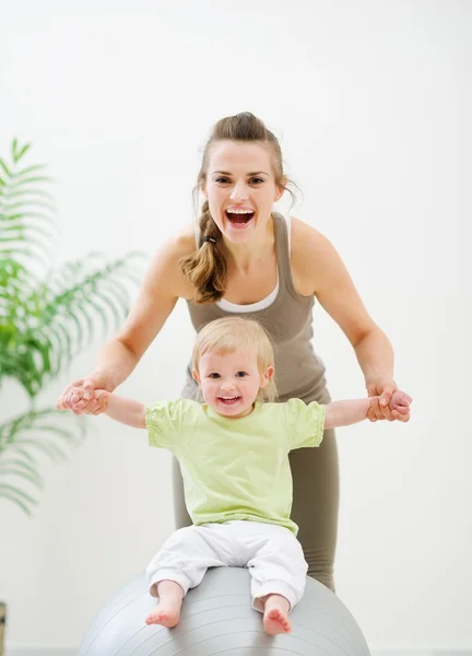 Fitness topu üzerinde oturan Anne Anne holding bebek — Stok fotoğraf