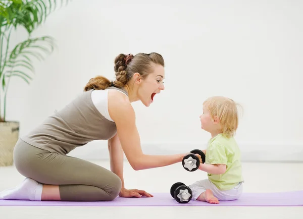 Baby helping mother lifting dumb-bells — Stock Photo, Image