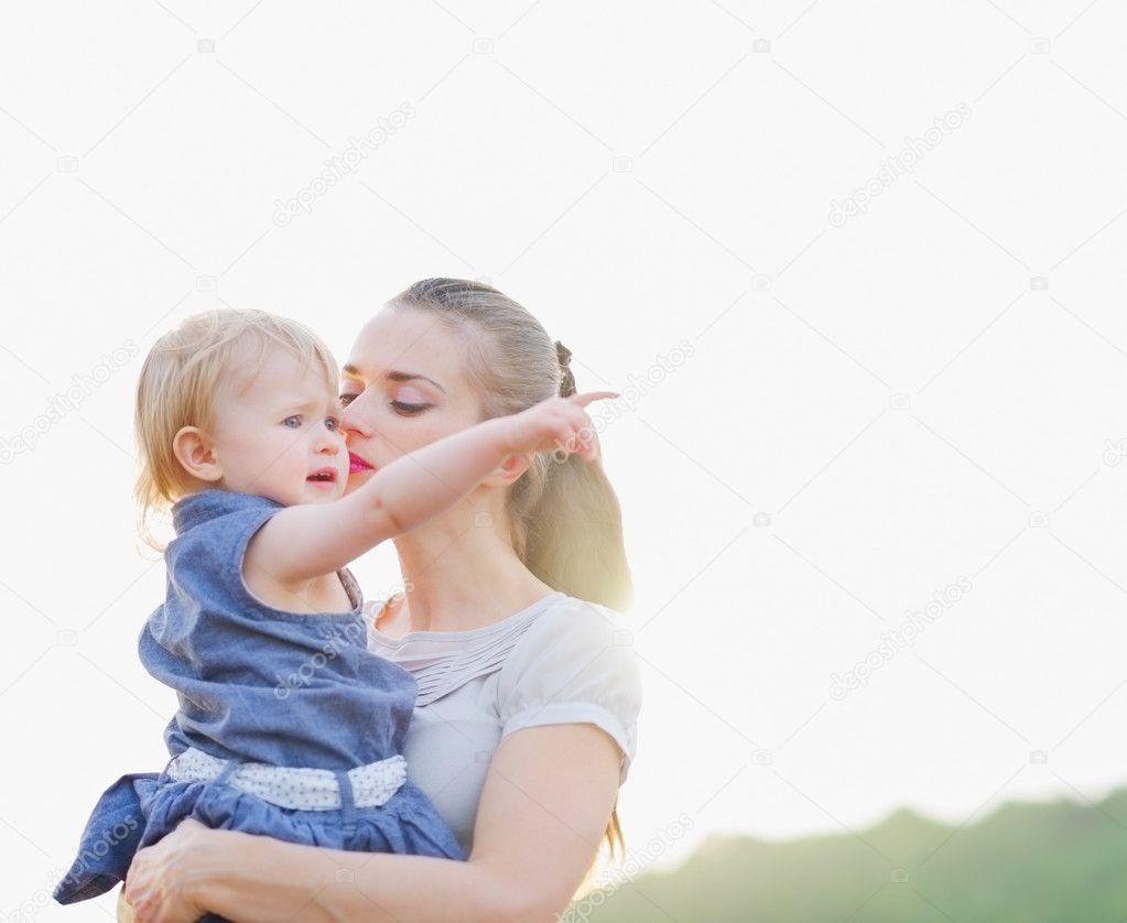 Portrait of mother kissing baby pointing on copy space
