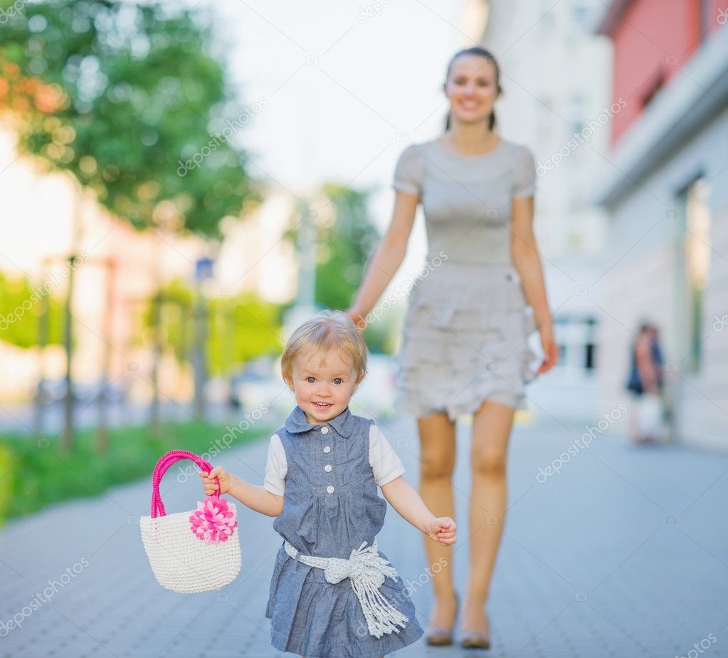 Happy baby walking with mom in city