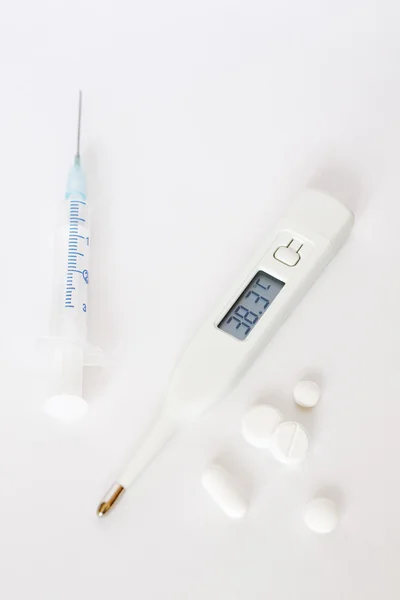 Termometr cyfrowy, strzykawki i białe tabletki — Zdjęcie stockowe