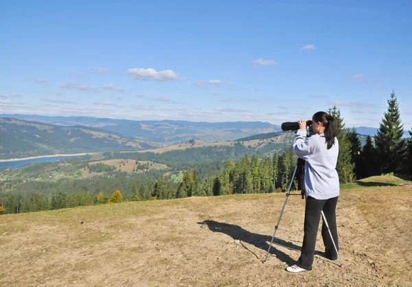 Ragazza con binocolo guardando in montagna . — Foto Stock