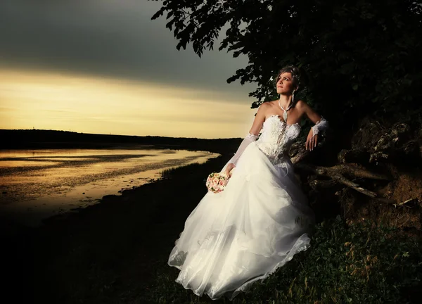La novia admirando la puesta de sol en la orilla del río —  Fotos de Stock