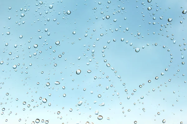 Heart from gentle droplets of a rain on clean transparent glass — Stock Photo, Image