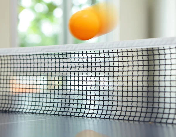 Laranja bola de tênis de mesa se movendo sobre net — Fotografia de Stock