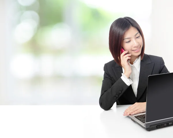 Business woman speaking phone and using computer — Stock Photo, Image