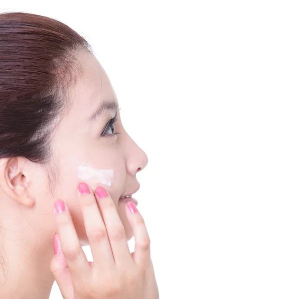 Mulher aplicando creme hidratante no rosto no perfil — Fotografia de Stock