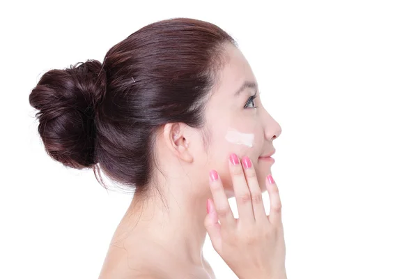 Mulher aplicando creme no rosto no perfil — Fotografia de Stock
