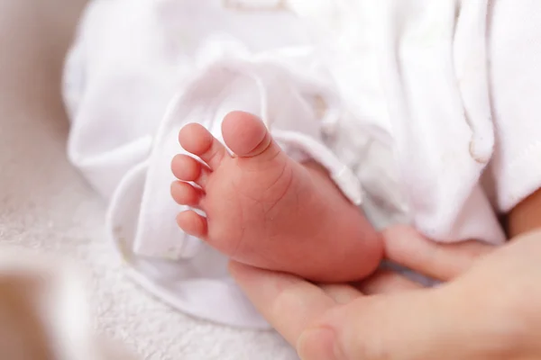 Pequeños pies de bebé y mano madre — Foto de Stock