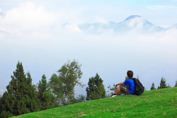 stock image Man sitting on grass and looking mountain