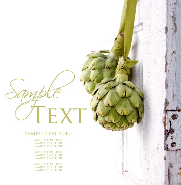 Two artichokes hanging from a vintage door — Stock Photo, Image