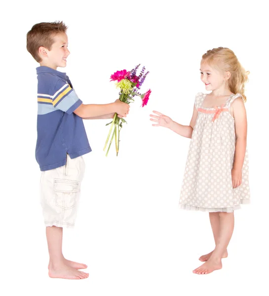 Kleine jongen bloemen overhandigen aan klein meisje — Stockfoto