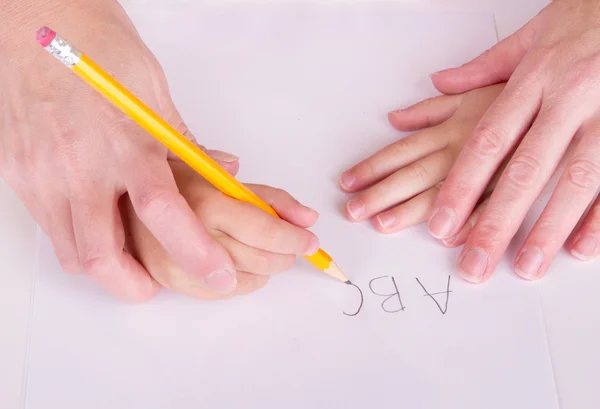 Мать или учитель помогают ребенку писать — стоковое фото