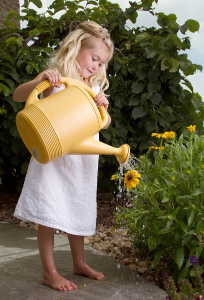 Jong meisje water geven bloemen — Stockfoto