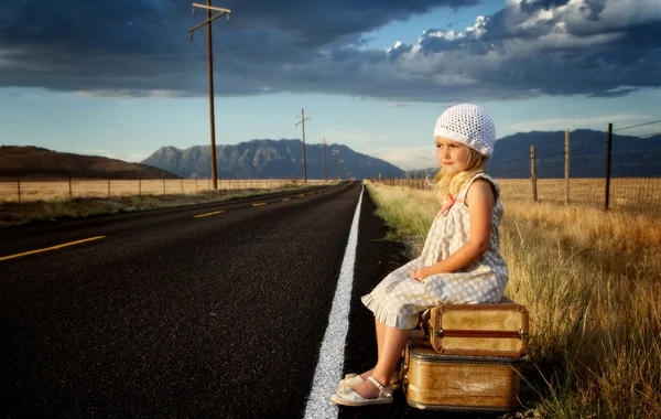 Young girl on side of road with suitcases — Stock Photo, Image