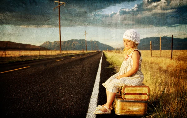 Young girl on side of road with suitcases — Stock Photo, Image