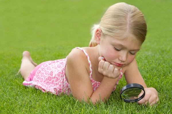 stock image Girl looking through magnifying glass outdoors