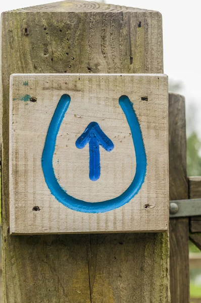 Blue horse shoe sign with arrow on gate post — Stock Photo, Image