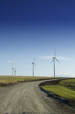 Wind generators at the end of a dirt road clipart