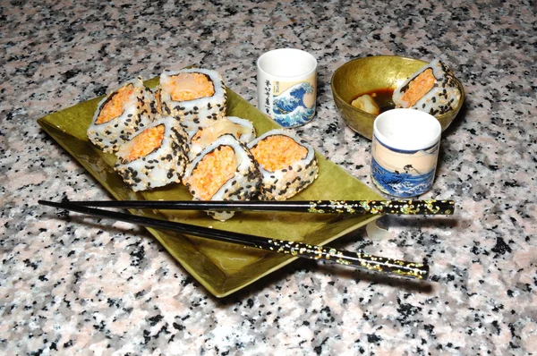 Talerz sushi, pałeczkami i saki kubki na białym tle — Zdjęcie stockowe