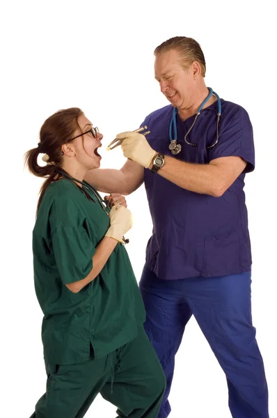 Mad dentist pulling tooth from nurse — Stock Photo, Image