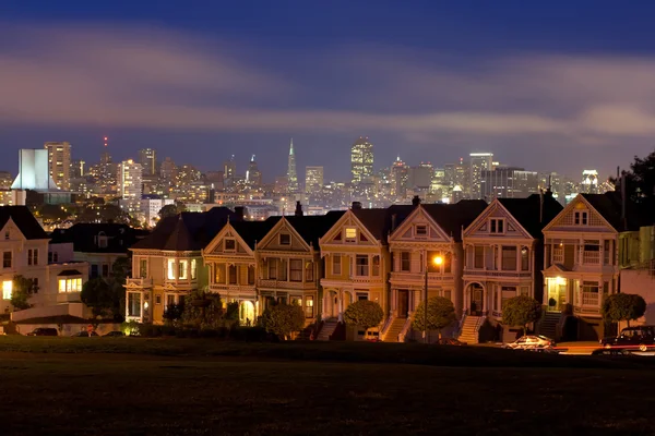 stock image Night descends on the iconic Painted Ladies row of Victorian houses backed by downtown San Francisco during blue hour in California