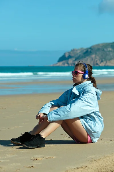 Fitness dívka s sluchátka na pláži — Stock fotografie