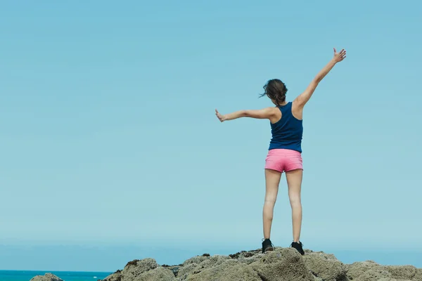 Fitness meisje bovenop de rotsen met armen wijd open — Stockfoto
