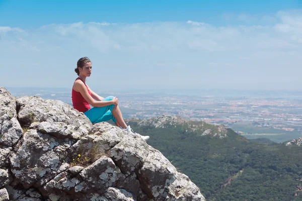 Young athletic girl relaxing on top of rocks — Stock Photo, Image