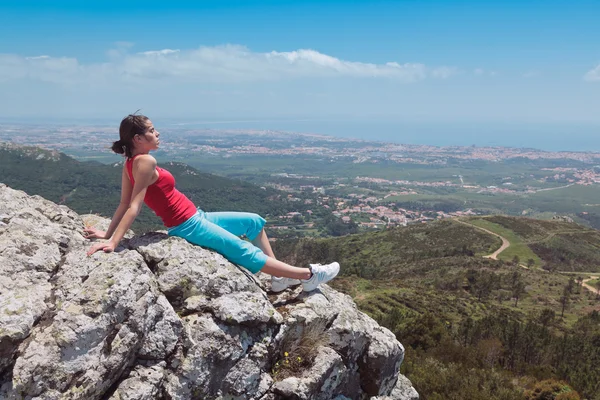 stock image Young athletic girl relaxing on top of rocks