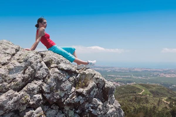 Stock image Young athletic girl relaxing on top of rocks