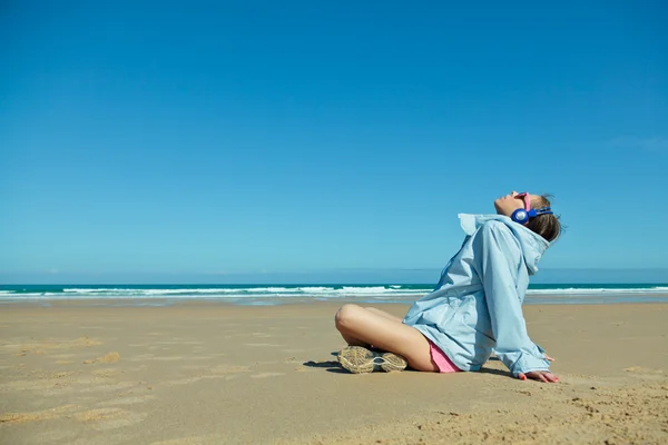 Fitness meisje met koptelefoon op het strand — Stockfoto