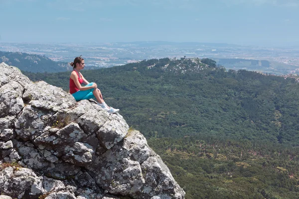 Stock image Young athletic girl relaxing on top of rocks