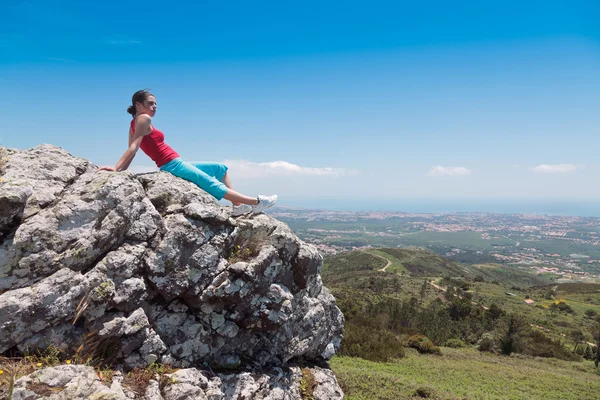 Stock image Young athletic girl relaxing on top of rocks