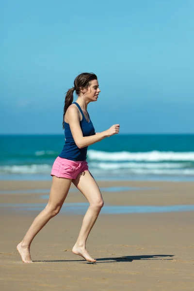 Flicka kör på stranden i barfota — Stockfoto