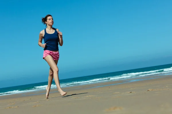 Flicka kör på stranden i barfota — Stockfoto