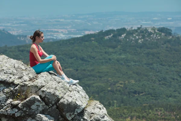 Jovem atlética relaxante no topo das rochas — Fotografia de Stock