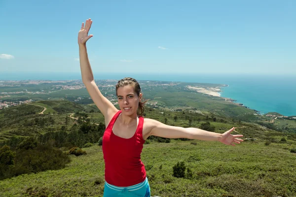Fitness meisje bovenop de rotsen met armen wijd open — Stockfoto