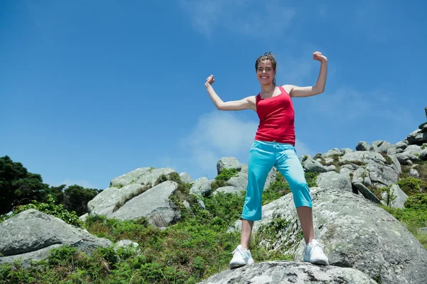 Fitness girl on top of rocks with arms wide open — Stock Photo, Image