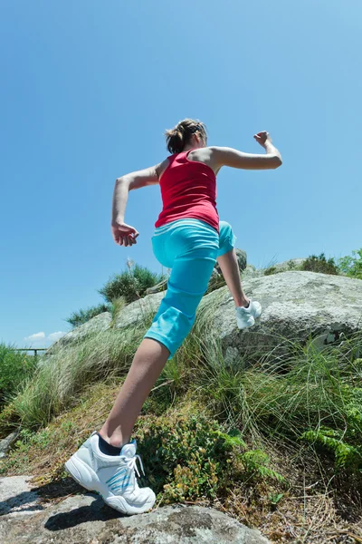 Athletic girl jogging on boulders — Stock Photo, Image