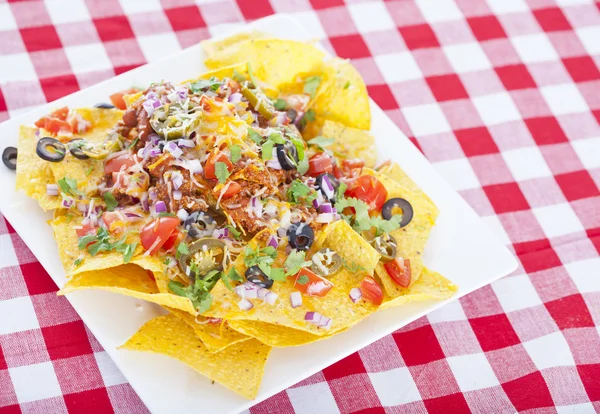 Cheesy Nachos on a Red Checkered Tablecloth — Stock Photo, Image