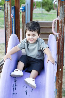 Cute baby playing on sliding board, smiling