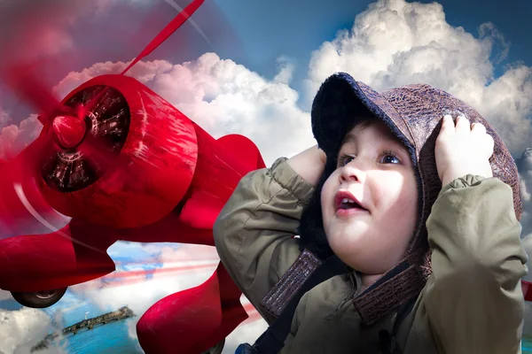 En bedårande pojke över en röd planeputting sina händer för att hans han — Stockfoto