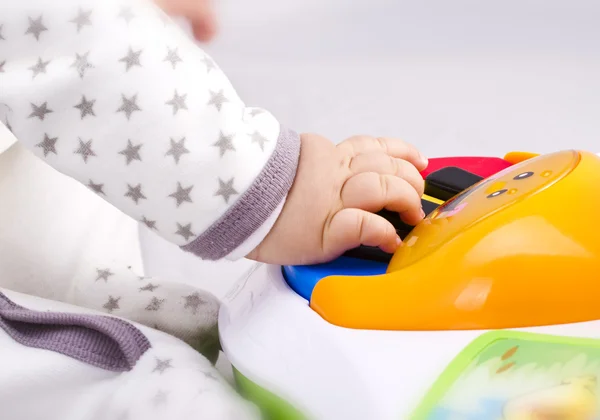 Новорожденный ребенок играет на игрушечном пианино — стоковое фото